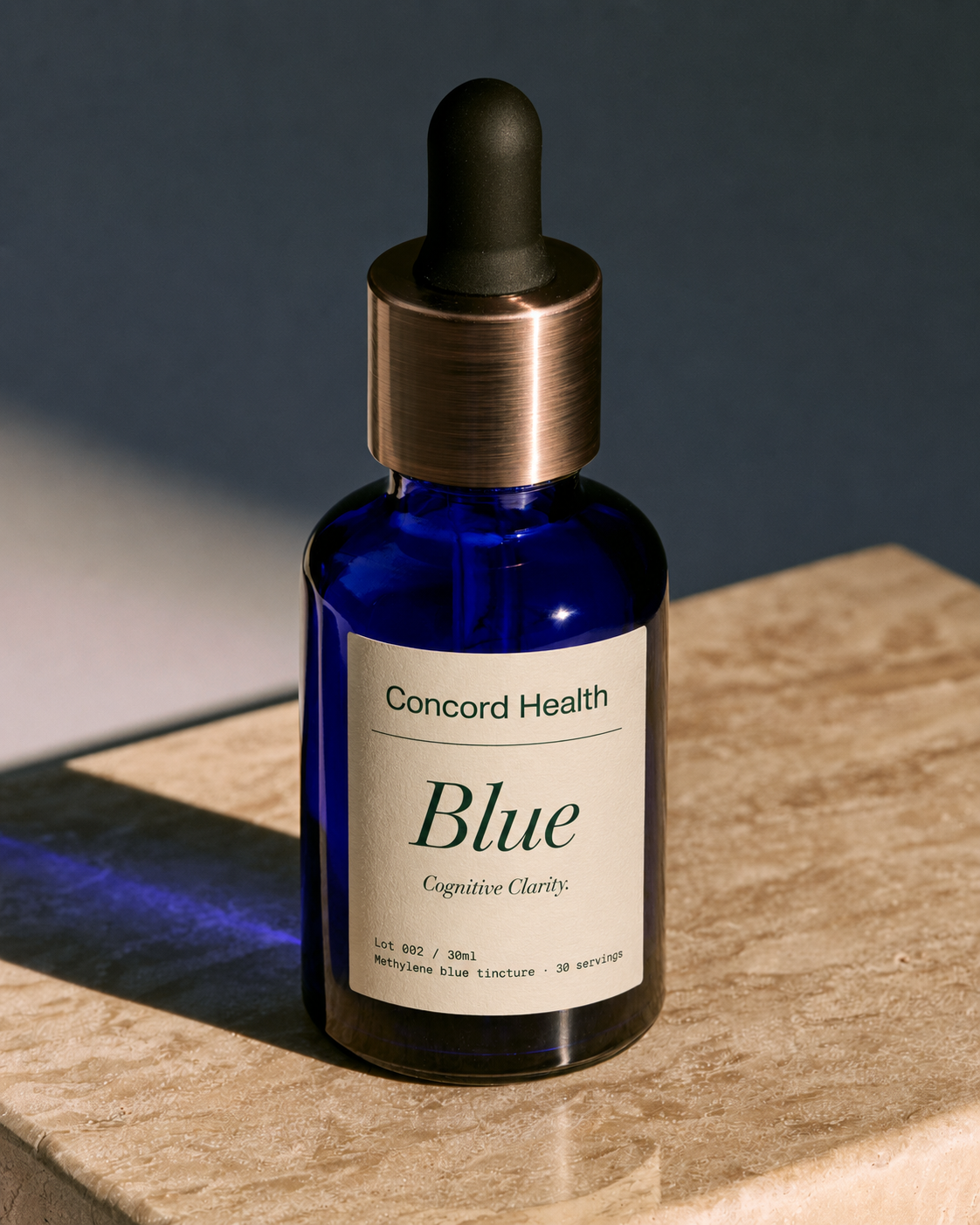 Concord Health Blue — a cobalt glass dropper bottle of methylene blue tincture on a warm bone stone slab.